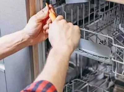 Person repairing a dishwasher interior.