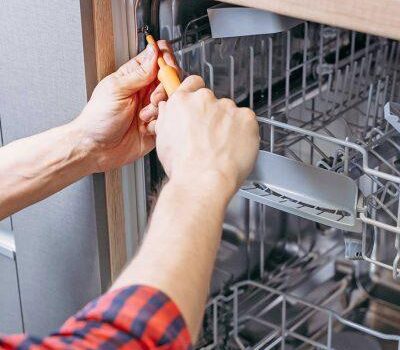 Person repairing a dishwasher interior.