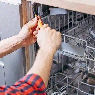 Person repairing a dishwasher interior.