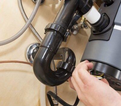 Hand connecting garbage disposal plumbing