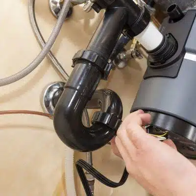 Garbage Disposal Services 1 Hand connecting garbage disposal plumbing