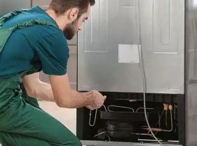 Technician repairing a refrigerator unit.